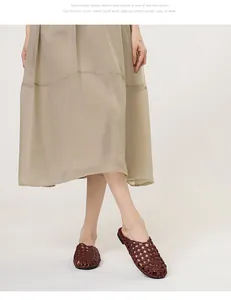 Modelo con mules planos de cuero trenzado marrón vintage con elegante diseño calado en el fondo