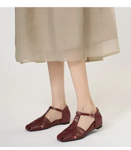 Close-up detail of vintage burgundy woven sandals with T-strap and square toe on model