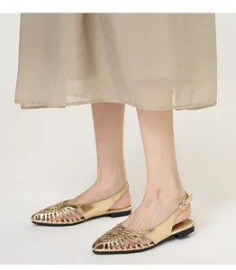 Detailed view of vintage gold woven pointed-toe flat slingback sandals on model