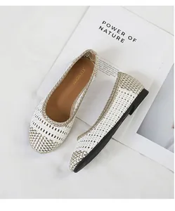 Un dettaglio macro di eleganti ballerine intrecciate con finiture in oro e bianco