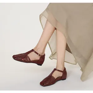 Elegant burgundy woven T-strap sandals styled with a flowing beige midi skirt in detail