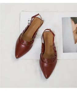 Macro view of brown pointed-toe slingback flats with scalloped hollow-out edges