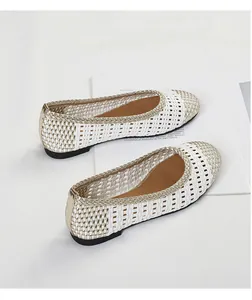 Primo piano di eleganti ballerine intrecciate bianche e oro con design traforato