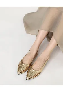 Close-up detail of gold woven pointed-toe slingback flat sandals on model feet.