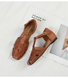 Detail of brown woven T-strap sandals with square toe and gold-tone buckle closure