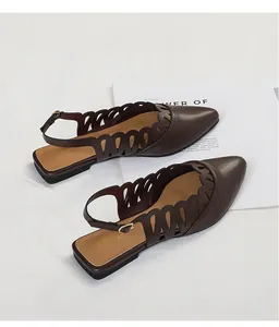 Close-up of dark brown pointed-toe slingback flats with hollow-out decorative pattern