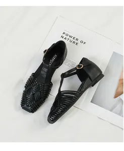 Elegant detail view of vintage black woven T-strap sandals with gold buckle closure