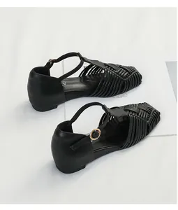 Macro view of black woven T-strap sandals featuring square toe design and buckle