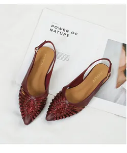 Detailed view of burgundy vintage woven pointed-toe slingback flat sandals on a magazine