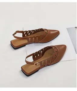 Detail of brown pointed-toe slingback flats with decorative hollow-out side patterns