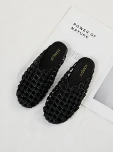 Primer plano de chinelas negras trenzadas de punta cerrada sobre fondo de revista