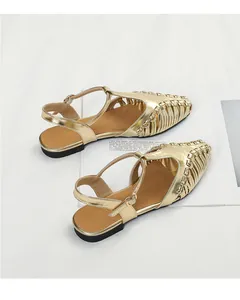 Detailed view of gold woven T-strap flat sandals with metallic finish