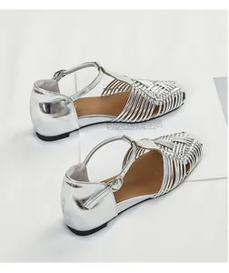 Detailed view of silver woven T-strap flat sandals with a vintage Roman style.