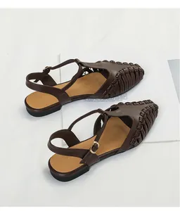 Detailed view of brown woven pointed-toe sandals with T-strap and buckle closure