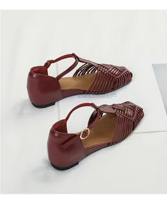Detailed view of burgundy woven leather sandals with T-strap and gold buckle design