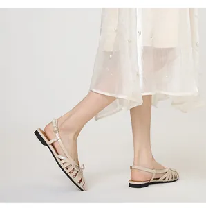 Detailed shot of beige French retro woven hollow flat sandals with a delicate bow