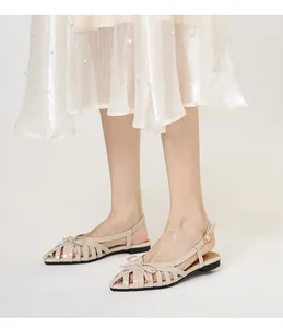 Elegant French beige woven cage sandals with bow detail shown on feet in studio light