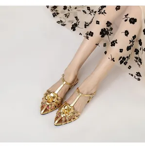 Detailed view of elegant gold camellia flat sandals featuring a Roman T-strap design