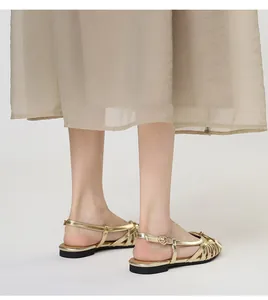 Elegant metallic gold woven hollow-out flat gladiator sandals shown on model feet