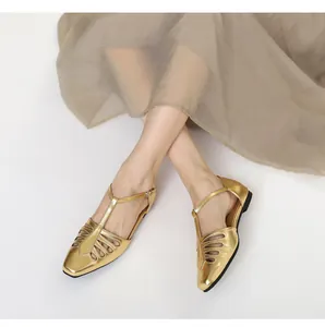 Detail view of vintage gold square toe sandals with cutout T-strap and flat sole.