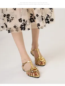 Detail view of gold camellia flower sandals with T-strap and flat sole on model