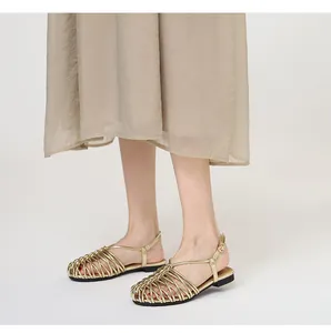 Detailed view of gold hand-woven flat Roman sandals with adjustable buckle strap