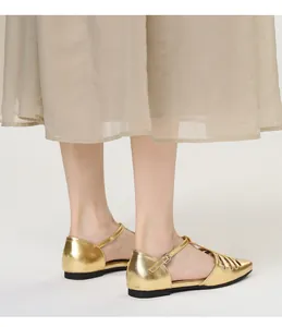 Close-up of gold metallic T-strap flat sandals with retro hollow design and square toe