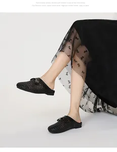 Modell trägt schwarze gewebte Mules mit zarter Schleife und hohlem Design