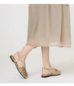 Side view of gold braided closed-toe flat sandals with adjustable ankle straps