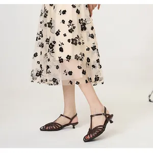 Elegant dark brown woven kitten heel sandals with a pointed closed toe on a model