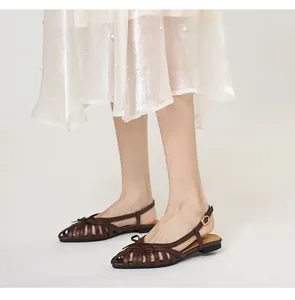 Close-up side view of brown woven vintage sandals with bow accent and ankle strap