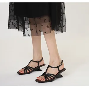 Macro detail view of black square-toe sandals with elegant cross straps and a unique heel.