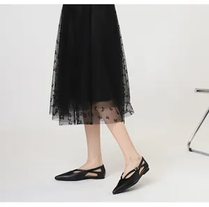 Seitenansicht schwarzer spitzer flacher Schuhe mit elegantem Kreuzriemen-Schnallen-Design.