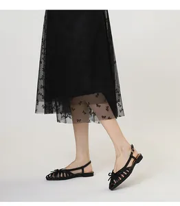 Detail shot of elegant black woven cage sandals with bow decoration and ankle strap
