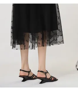Close-up of black strappy sandals with a unique irregular architectural wedge heel