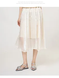 Silver metallic camellia flower flat sandals paired with an elegant pearl-embellished skirt
