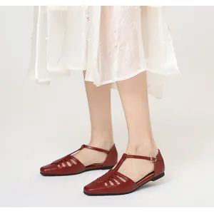 Detail shot of vintage red T-strap flat sandals with hollow-out pattern on square toe.