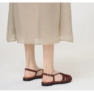 Close-up detail of handmade woven burgundy Roman sandals on model in studio setting