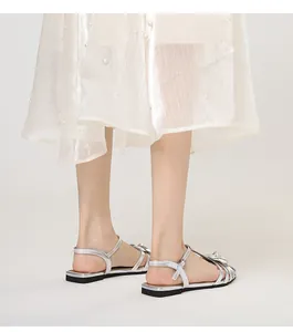 Close-up of silver flat sandals with camellia flower detail and ankle strap