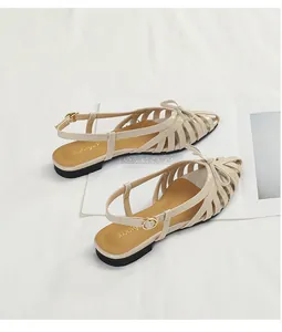 Detail view of beige braided hollow sandals with bow accent on a magazine background