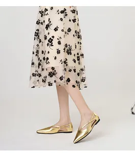 Elegante goldene spitze Ballerinas mit Kreuzriemen und Cut-out-Detail am Modell präsentiert.