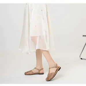 Detailed view of vintage hollow-out closed toe T-strap flat sandals on a female model
