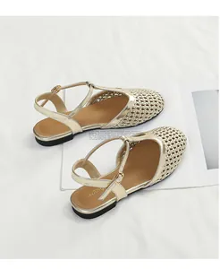 Vista dettagliata di sandali bassi intrecciati dorati con design a T-strap su sfondo bianco