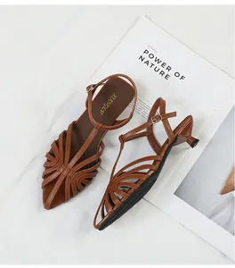 Close-up detail of brown woven pointed-toe kitten heel sandals on magazine prop.