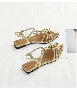 Top view detail of golden camellia flat sandals featuring delicate straps and buckle