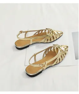 Detail shot of golden woven retro sandals with elegant bow accent on white backdrop