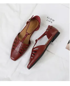 Close-up detail of red vintage T-strap flat sandals with square toe and hollow-out design.