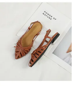 Detail view of brown woven hollow out sandals with bow accent in retro French style.
