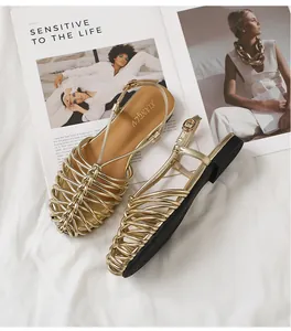 Detailed texture of gold hand-woven closed-toe Roman sandals on a white background