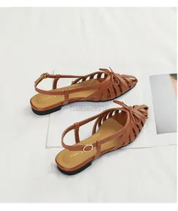 Elegant brown French style hollow woven sandals with bow detail and ankle strap.
